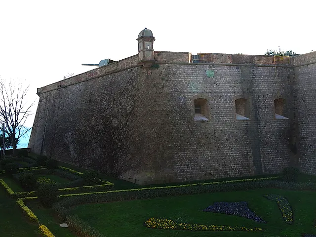 Le spesse mura di pietra del Castello di Montjuïc sopra il fossato e i giardini